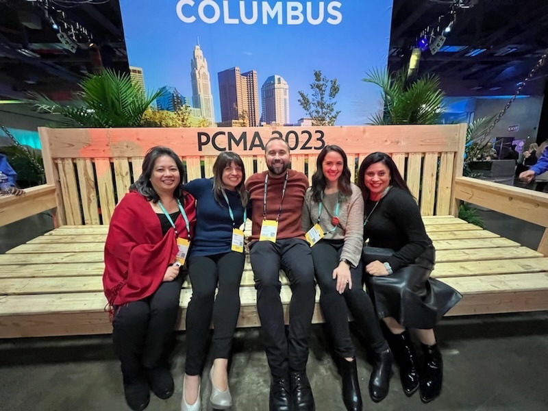 Group of people sitting on a stage smiling at the camera