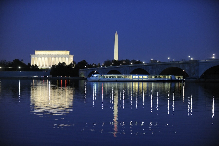 a view overlooking the water with a tour boat and the monuments in the background