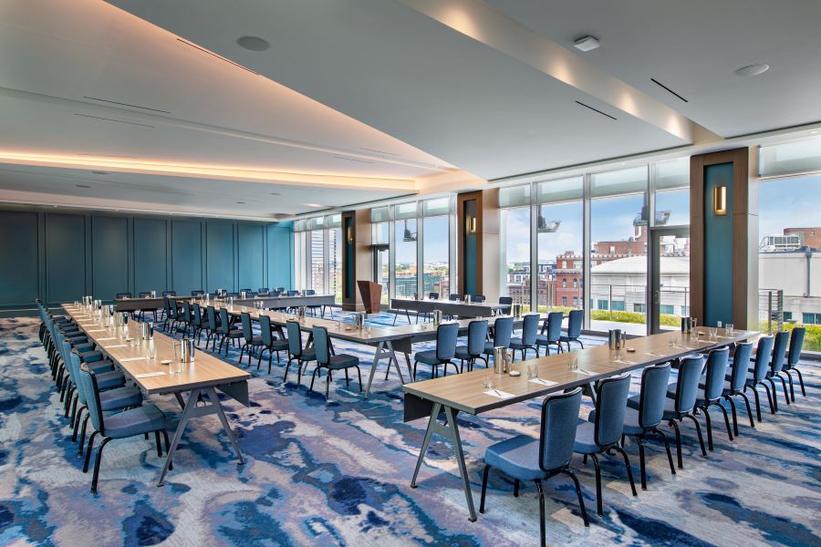 A bright and spacious conference room at the Royal Sonesta, featuring modern decor, a U-shaped table setup, and large windows offering views of the city skyline.